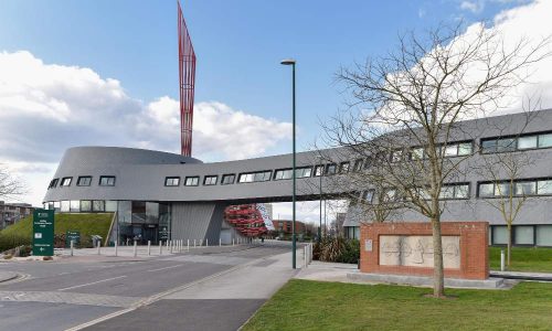 Bâtiment moderne au bord de la route contre un ciel nuageux