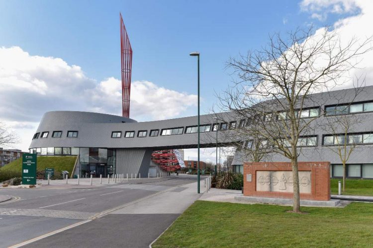 Bâtiment moderne au bord de la route contre un ciel nuageux